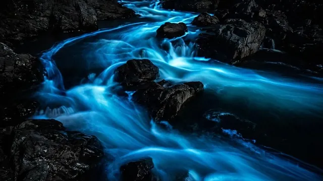 A river of glowing light flowing smoothly around dark stones