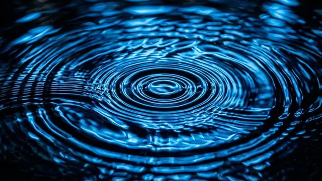 Concentric ripples in dark water lit by electric blue light